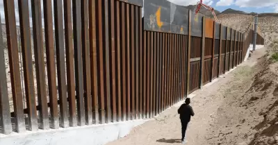 Migrante en el muro fronterizo