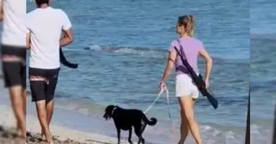 La mujer extranjera caminando por la playa con un rifle