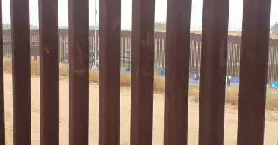 Migrantes en el muro fronterizo