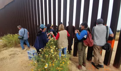 Migrantes en el muro fronterizo