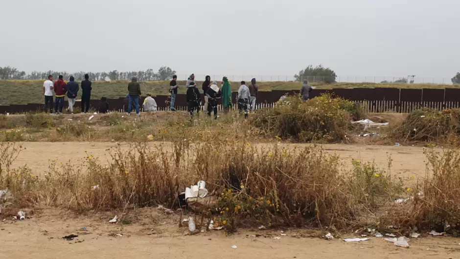 Migrantes en el muro fronterizo