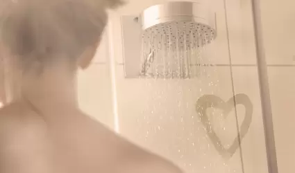 Mujer en ducha con un corazn de amor en el vapor del mampara de ducha.