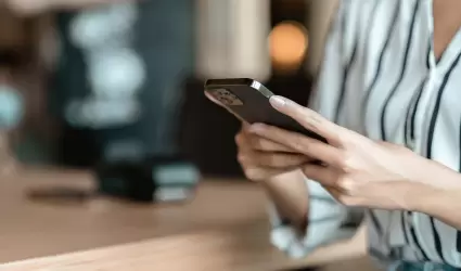 mujer usando un smartphone en una cafetera