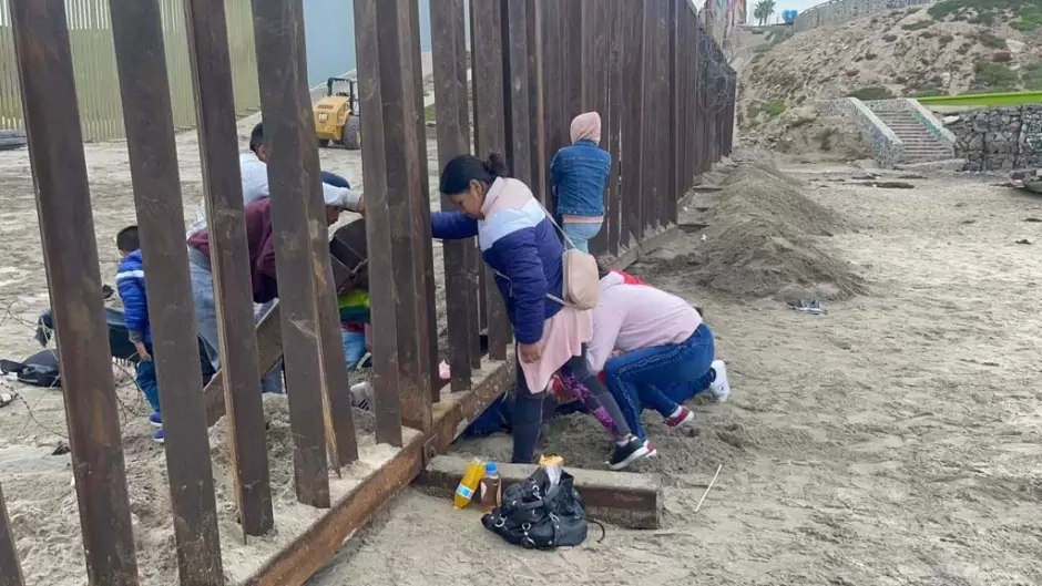 Familia con nios escarba arena para cruzar muro fronterizo y entregarse