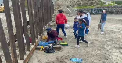 Familia con nios escarba arena para cruzar muro fronterizo y entregarse