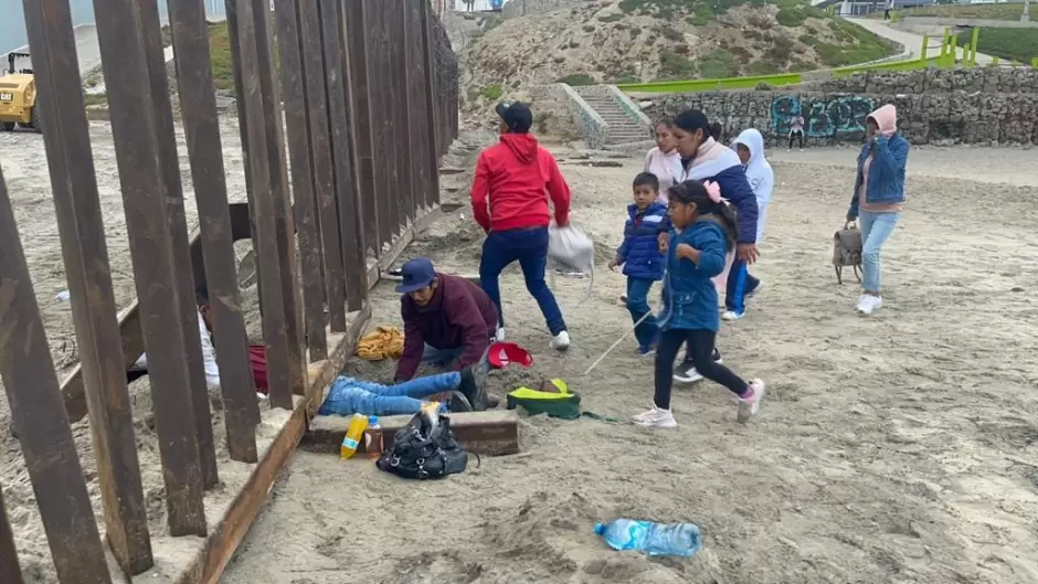 Familia con nios escarba arena para cruzar muro fronterizo y entregarse