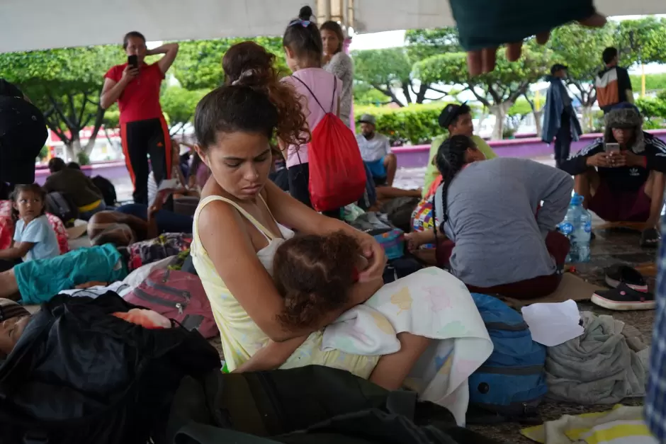 Migrante embarazada que viaja con dos hijas y su esposo resguardndose de la lluvia en la plaza de Ciudad Hidalgo a un lado del ro Suchiate.