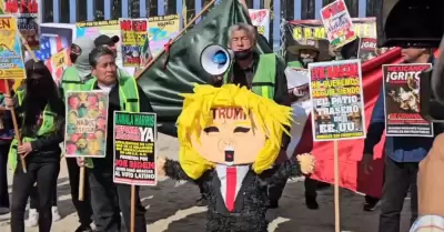 Activistas queman piata con la figura de Trump frente al muro internacional en 